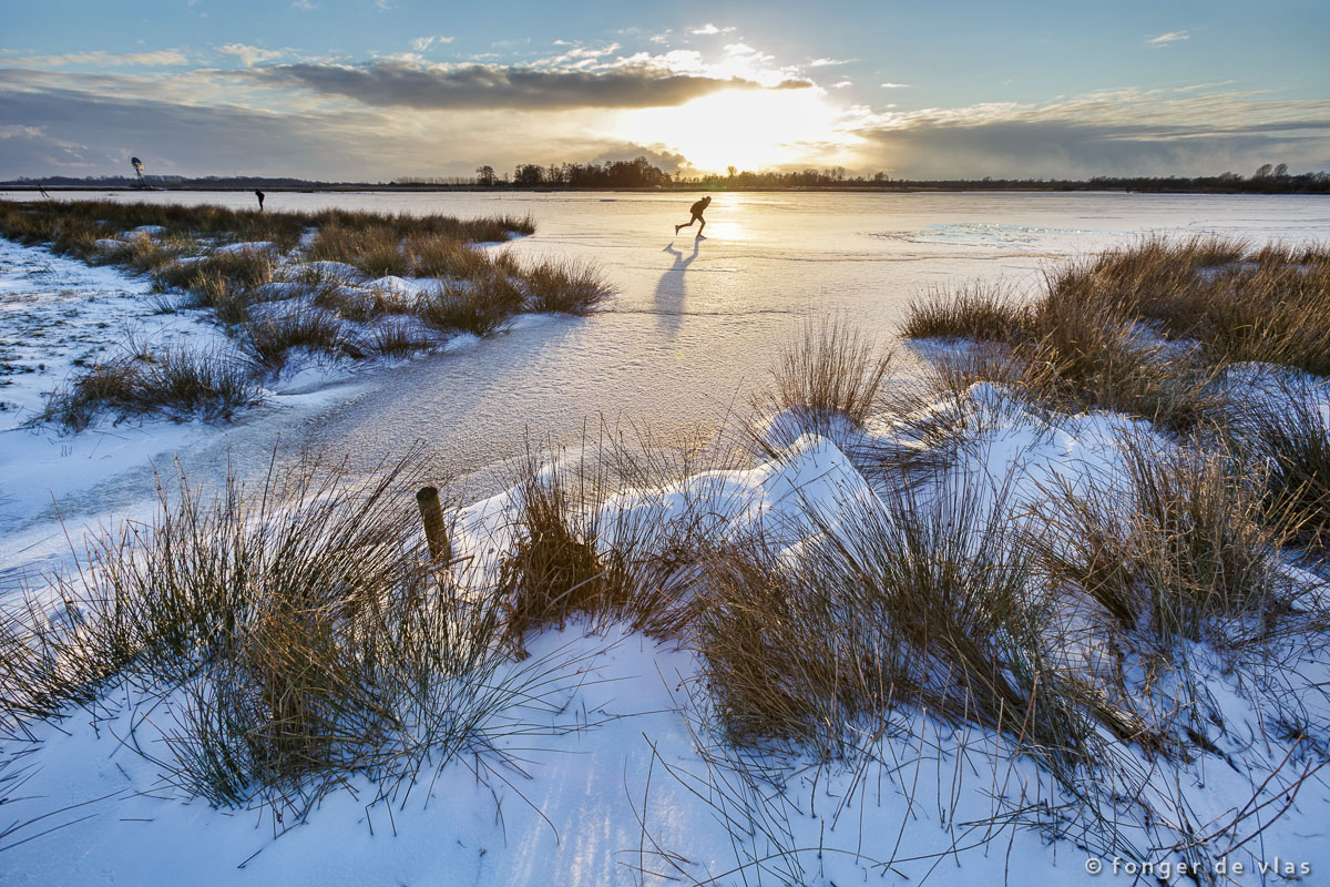 Schaatser op natuurijs in De Alde Feanen bij ondergaande zon